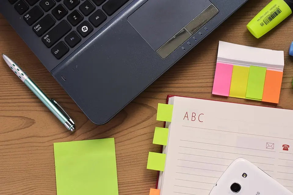 Bureau avec un ordinateur portable ouvert, un carnet et un stylo