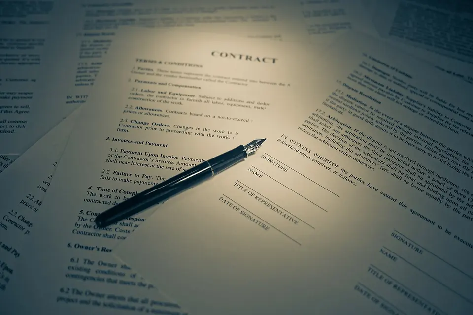 Main tenant un stylo au-dessus d'un contrat imprimé posé sur un bureau